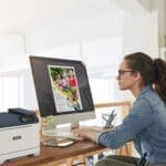 A woman seated at a desk, focused on her work, with a Xerox® C320 Colour Printer A woman seated at a desk, focused on her work, with a Xerox® C320 Colour Printer