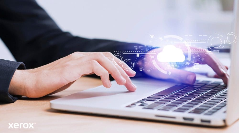 Xerox® Workplace Solutions: Cloud Connectivity A person's hands are shown typing on a laptop keyboard, with a glowing cloud icon and network connections superimposed over the image, symbolizing cloud connectivity and digital workflows.