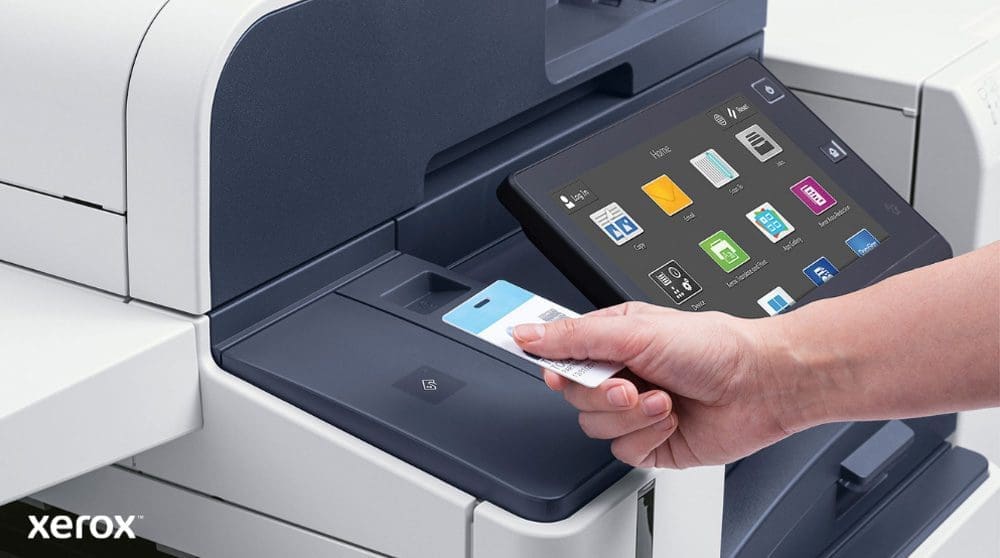 Xerox® Workplace Solutions: Secure Authentication and Smart Interface A hand holds a security card, scanning it near the card reader of a modern Xerox multifunction printer with a large touchscreen display showing various application icons.
